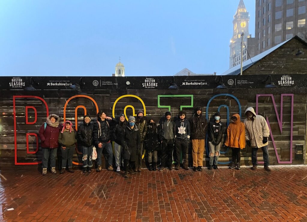 A group of people standing in front of a sign

Description automatically generated with medium confidence